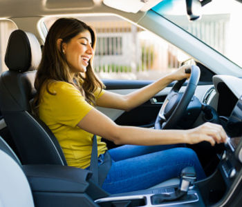 Giovane donna sorridente alla guida di un'automobile