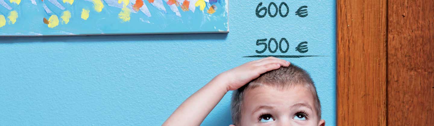 Bambino appoggiato a una parete decorata con cifre in euro in corrispondenza dell'altezza Bambino appoggiato a una parete decorata con cifre in euro in corrispondenza dell'altezza