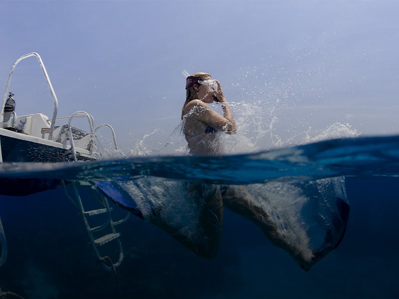 Promo Amex: donna con pinne e maschera che si tuffa in mare
