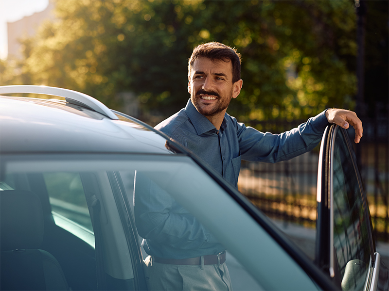 Fotografia di un uomo sorridente appoggiato alla portiera dell'autovettura