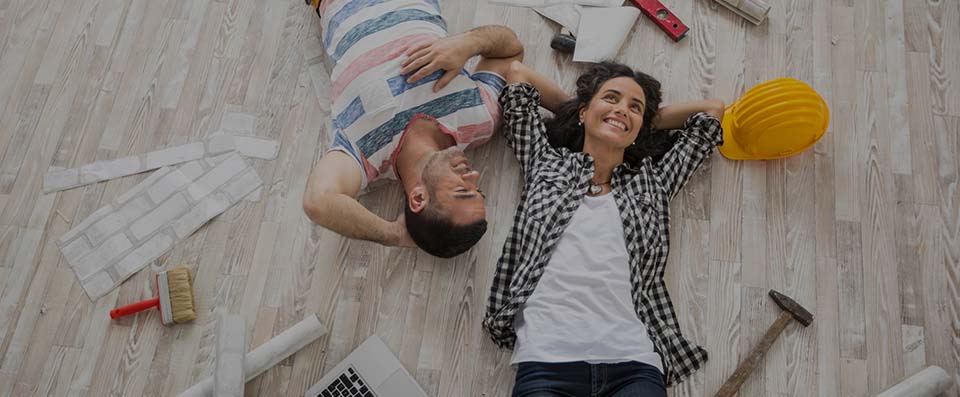 Giovane coppia sorridente sdraiata sul pavimento della casa in costruzione o ristrutturazione