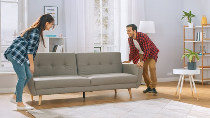 Giovane coppia uomo e donna posizionano il loro nuovo divano nel soggiorno