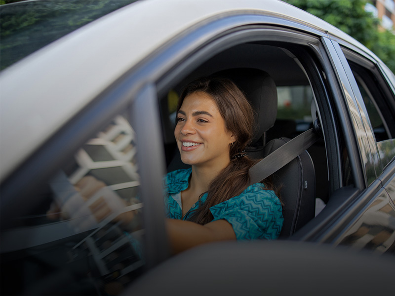giovane donna sorridente alla guida di un'automobile