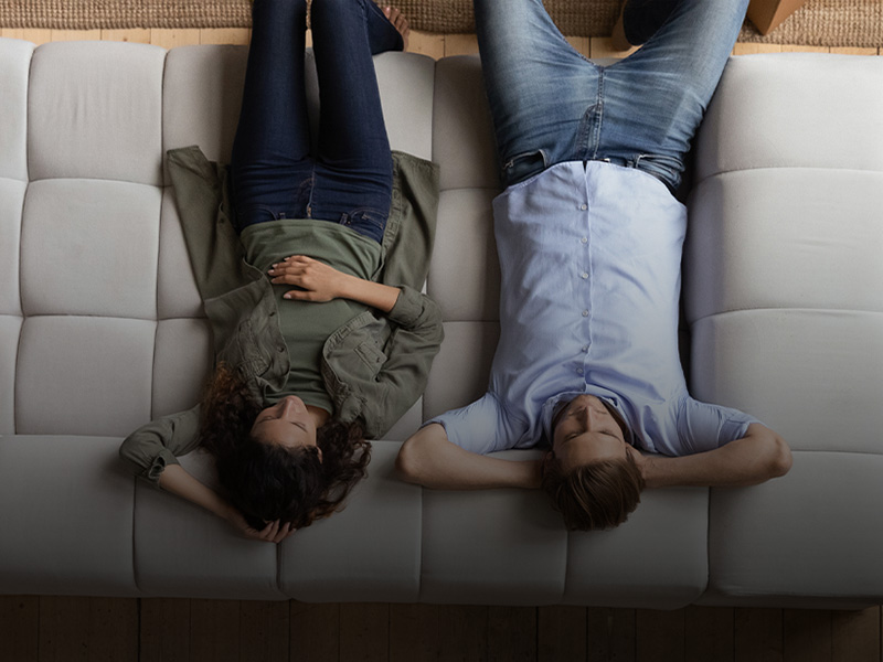 Un ragazzo e una ragazza seduti comodamente sul divano di casa, visti dall'alto
