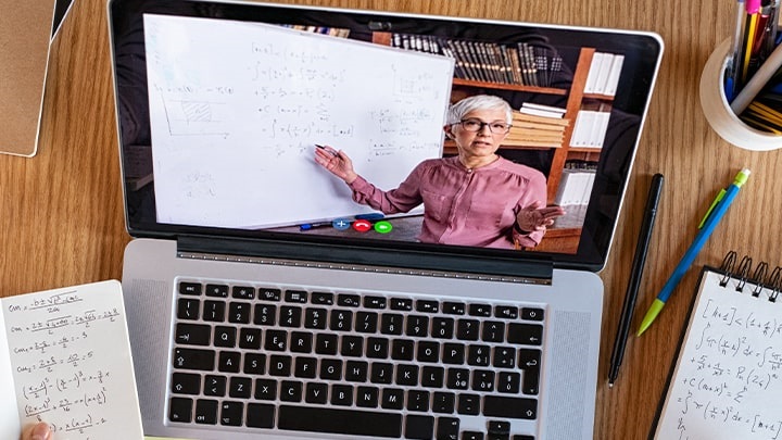 Sullo schermo di un computer portatile è visualizzata l'immagine di una professoressa che spiega una lezione