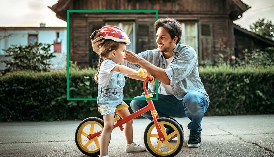 Padre che mette il casco alla figlia in bicicletta