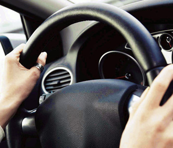 Mani femminili appoggiate su un volante di automobile