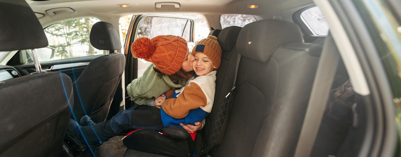 Mamma che bacia il suo bambino seduto sul seggiolino in auto