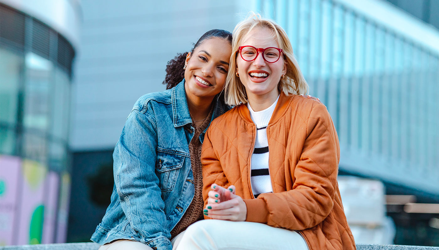 Due amiche sorridenti in un contesto urbano all'aperto