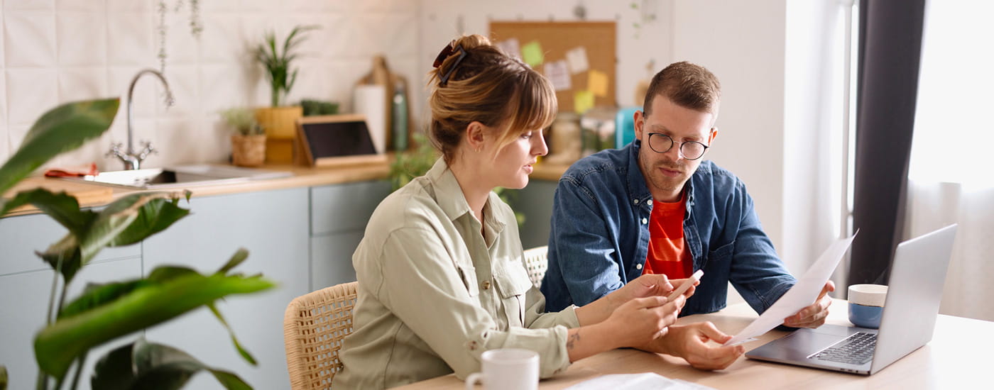 Uomo e donna che consultano documenti in cucina