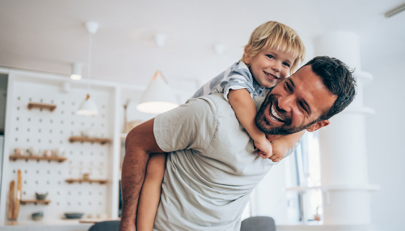 Giovane padre con il bambino a cavalcioni