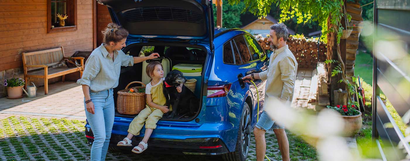 Famiglia con auto elettrica blu nel giardino di casa