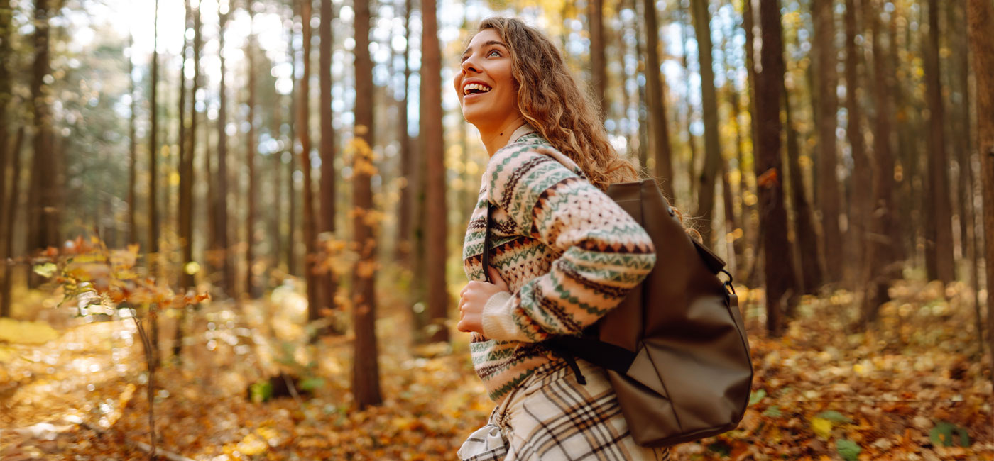 ragazza con zaino in spalla passeggia in un bosco autunnale