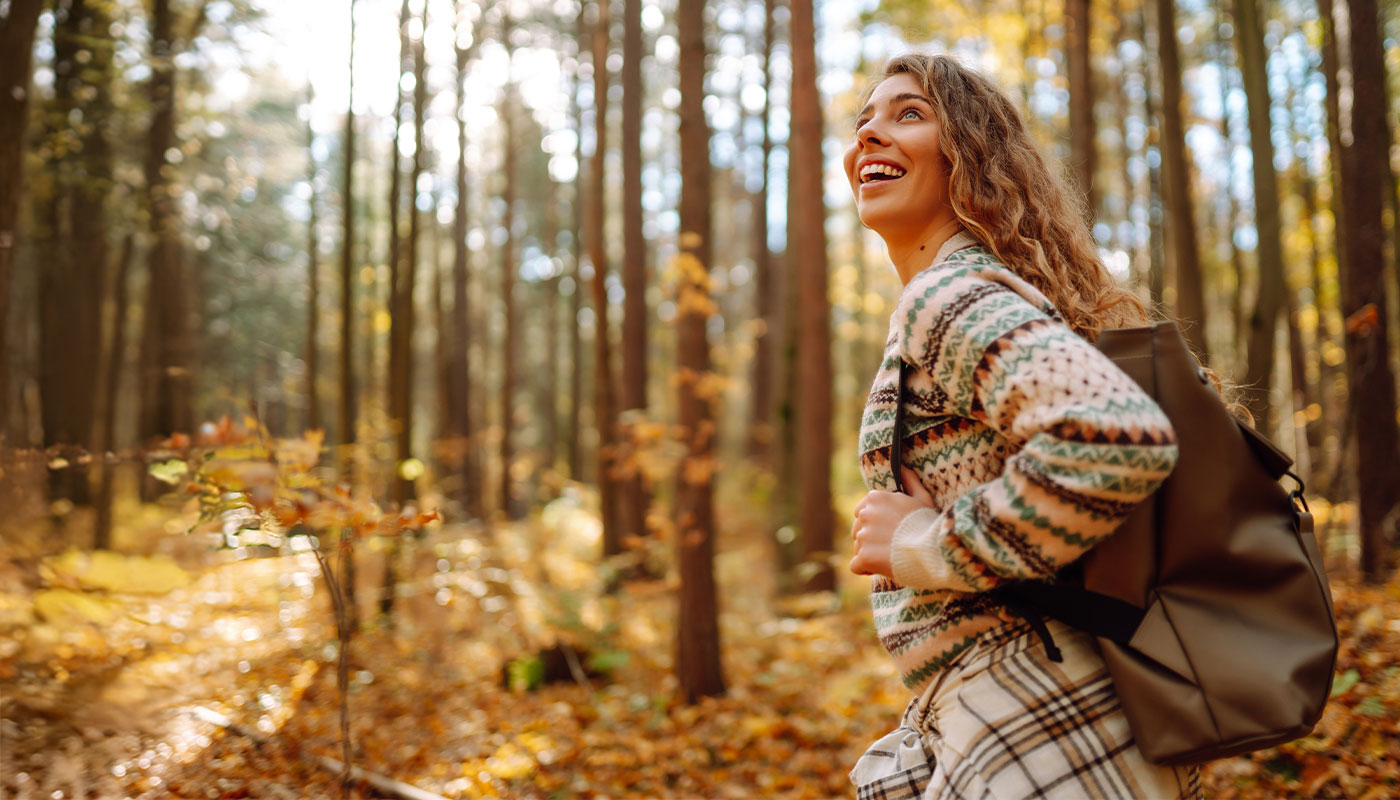 ragazza con zaino in spalla passeggia in un bosco autunnale