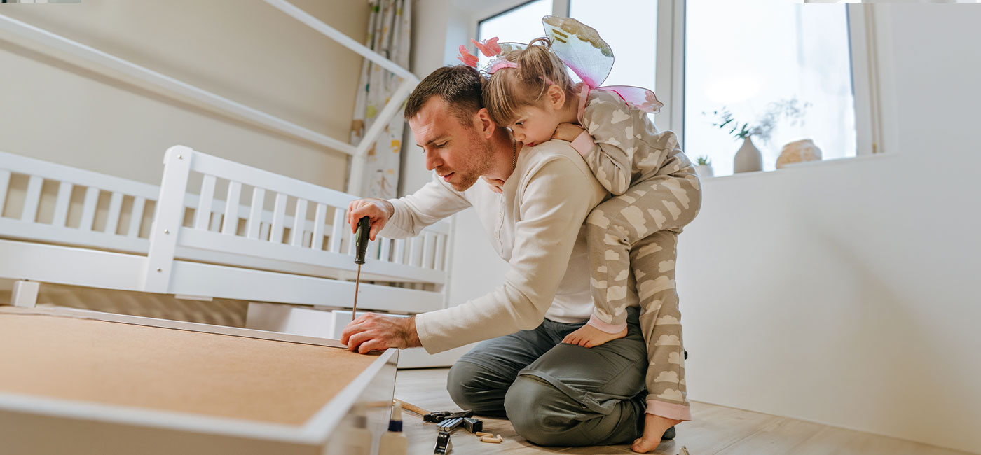 papà che monta un mobile nella cameretta della figlia