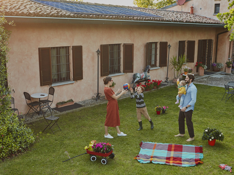 Giovane coppia con figli gioca nel giardino antistante una casa in campagna